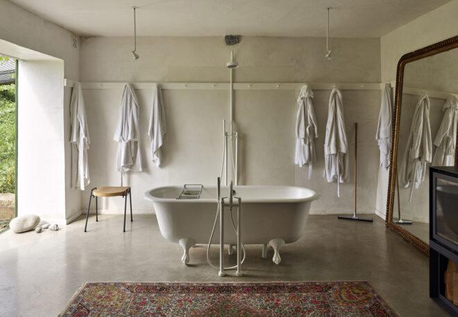 A bathroom with free-standing bathtub and a red patterned rug.