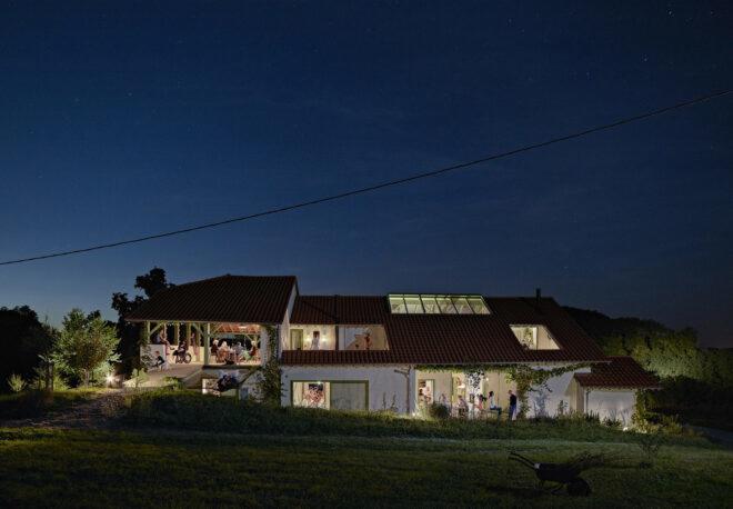 The exterior of a renovated farmhouse at night.