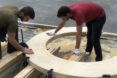 Two people putting together pieces of the wood Circula bench.