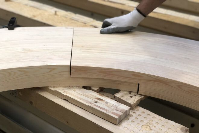 A hand putting together pieces of the wood Circula bench.