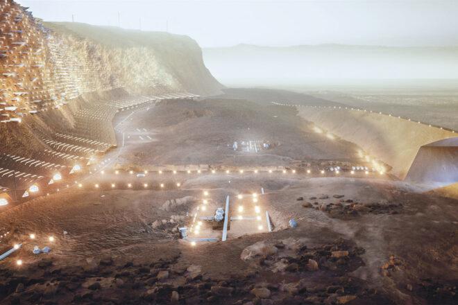 A bird's-eye view of lights, buildings and a bridge with tunnel on a rocky landscape.