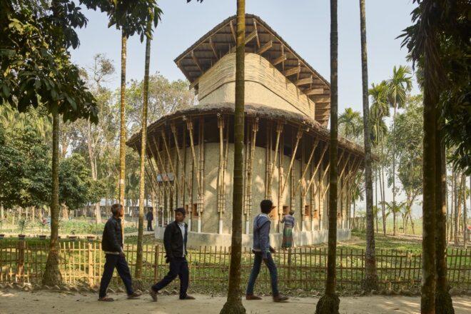 people walking on path near curved building made of mud and bamboo