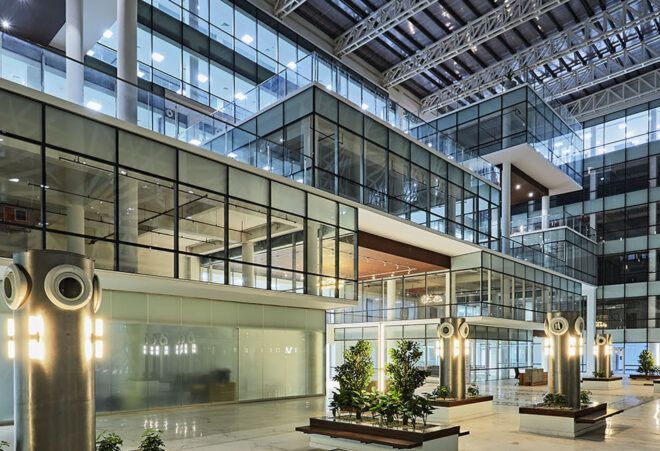 The ground floor of a multi-floor industrial space, with sparse greenery throughout the main level.