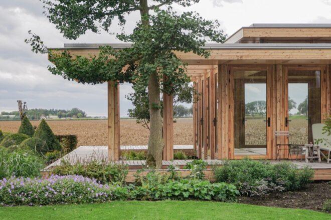 timber load-bearing supports on a glass home with a flat green roof