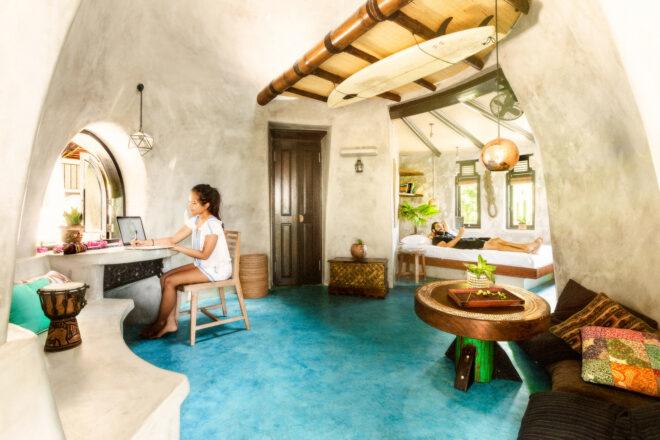 person on computer at small desk inside rammed earth dome
