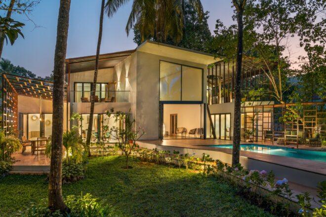 two-story white home with pool all lit up at night