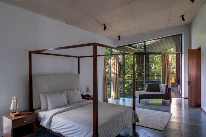 four-poster bed in large white room with one wall of glass