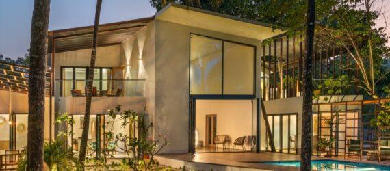 two-story white home with pool all lit up at night