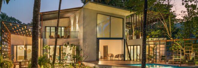 two-story white home with pool all lit up at night