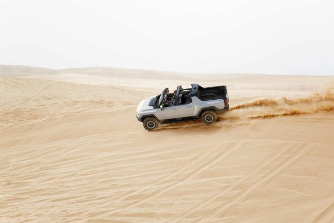 white electric Hummer driving on sand dunes