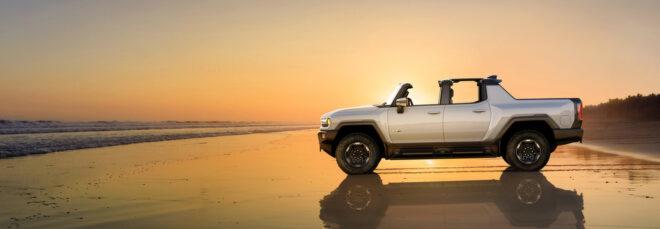 white Electric Hummer parked on a beach at sunset