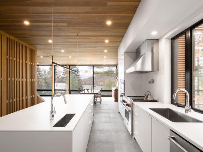 bright white kitchen in room with glass wall and wood ceiling