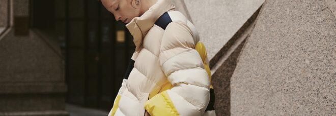 person wearing beige, yellow and navy puffer jacket
