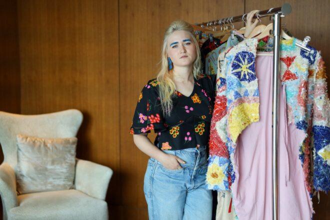 designer Madde Williams standing beside rack of clothing