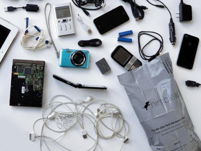 old tech gadgets spilling from recyclable bag