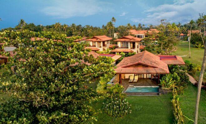 aerial view of hotel suites with gabled roofs in a tropical forest area
