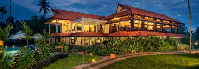 large resort building surrounded by tropical plants at night