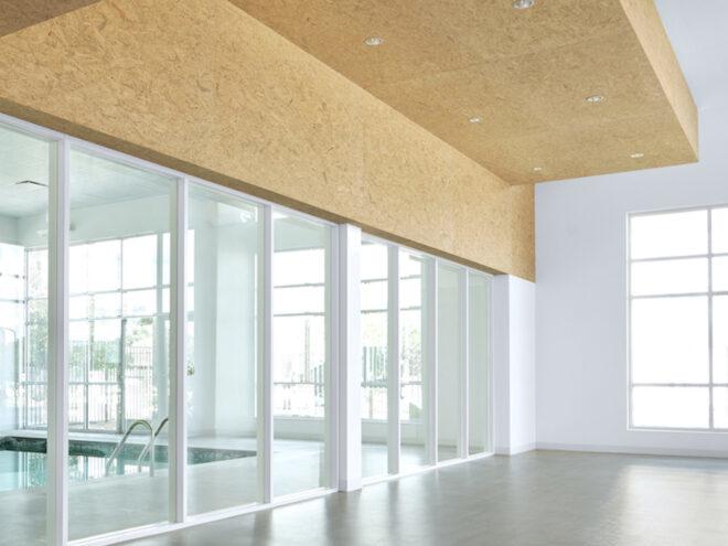 white room with unfinished wood ceiling and a wall of glass