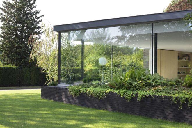 A view of large glazed exterior walls surrounded by lush greenery.