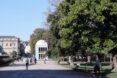 people walking in a park toward a white building with domed roof