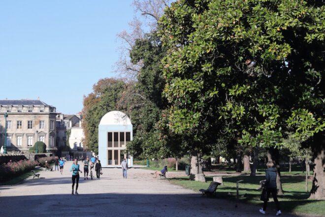 people walking in a park toward a white building with domed roof