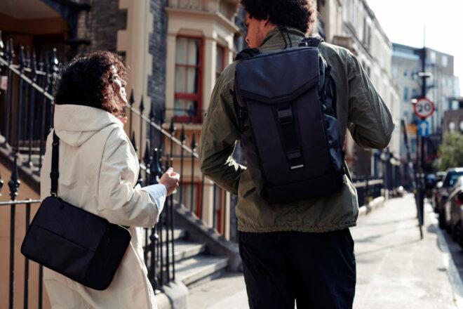 one person wearing backpack and other carry laptop bag