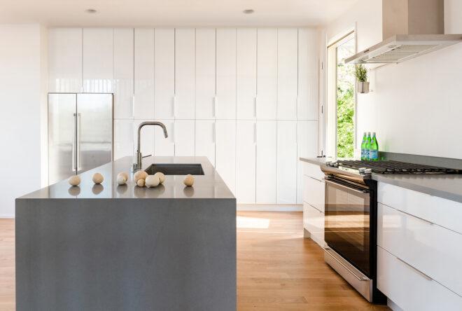 A kitchen with a gray island with built-in sink. To the right, countertops and a stove.