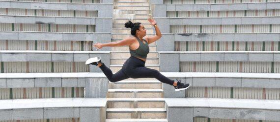 A person jumping while wearing green and black athletic clothes.