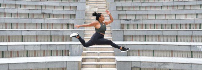 A person jumping while wearing green and black athletic clothes.