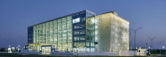 An angular streetview of a large rectangular building with a glass facade.