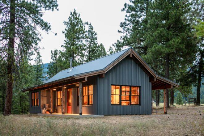 dark wood and metal cabin lit from within in the woods