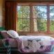 bed with quilt in room with large windows