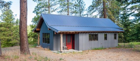 dark wood and metal cabin with gabled roof in the woods