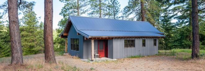 dark wood and metal cabin with gabled roof in the woods