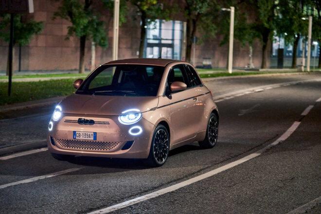 rose gold Fiat with LED headlights driving down road at night