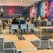 people dining in gray cafe room with colorful flags on the wall