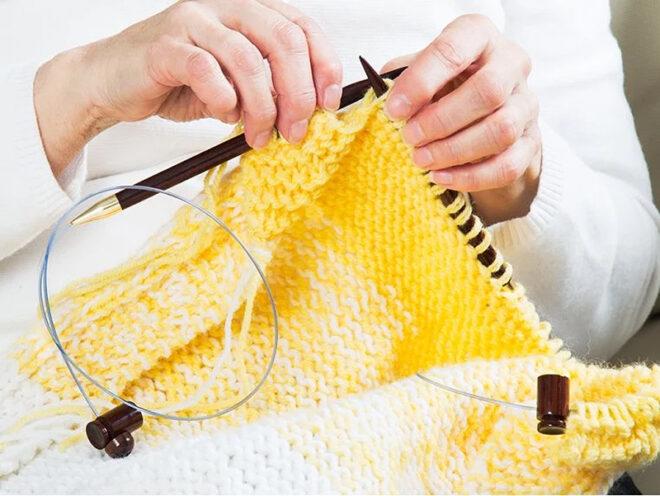 person knitting yellow scarf