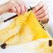 person knitting yellow scarf