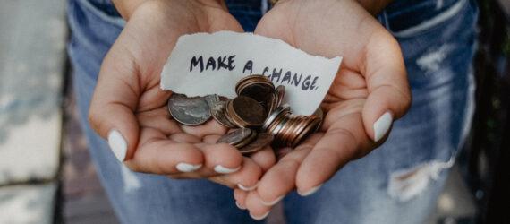 Person holding change and sign that says 