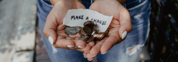 Person holding change and sign that says 