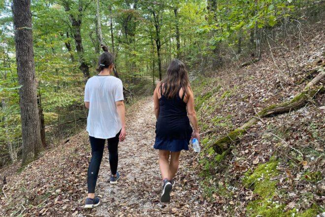 two people walking on forest trail