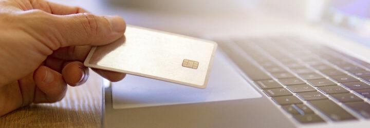 person holding credit card near laptop