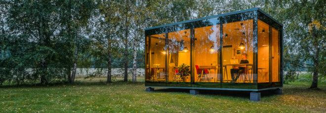 glass cabin with transparent walls lit up at dusk