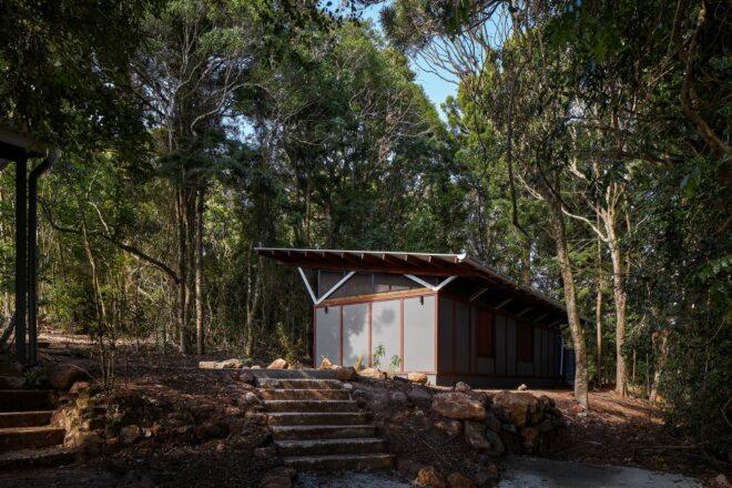 small gray building with slanted roof in a forest
