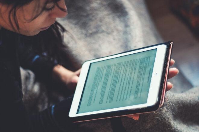 A person holding and looking down at a tablet.