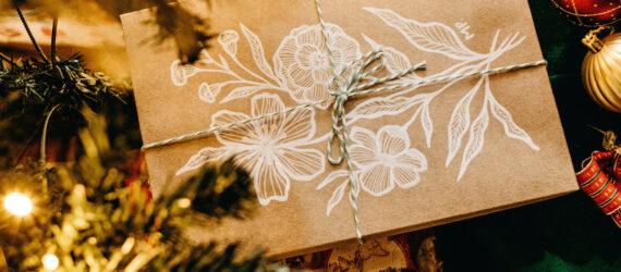 A close-up of a brown paper package surrounded by pine and baubles.