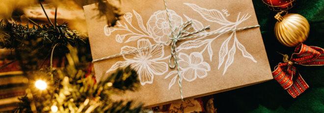 A close-up of a brown paper package surrounded by pine and baubles.