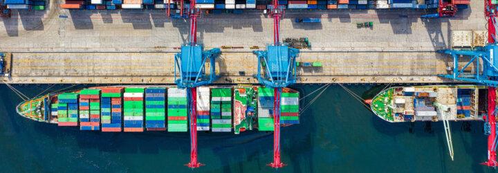 A bird's-eye view of a shipping area with cranes loading containers onto ships.
