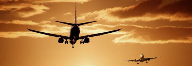 Two airplanes flying against a sunset sky.
