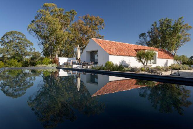A large pool of water next to a simple A-line house with a red roof.
